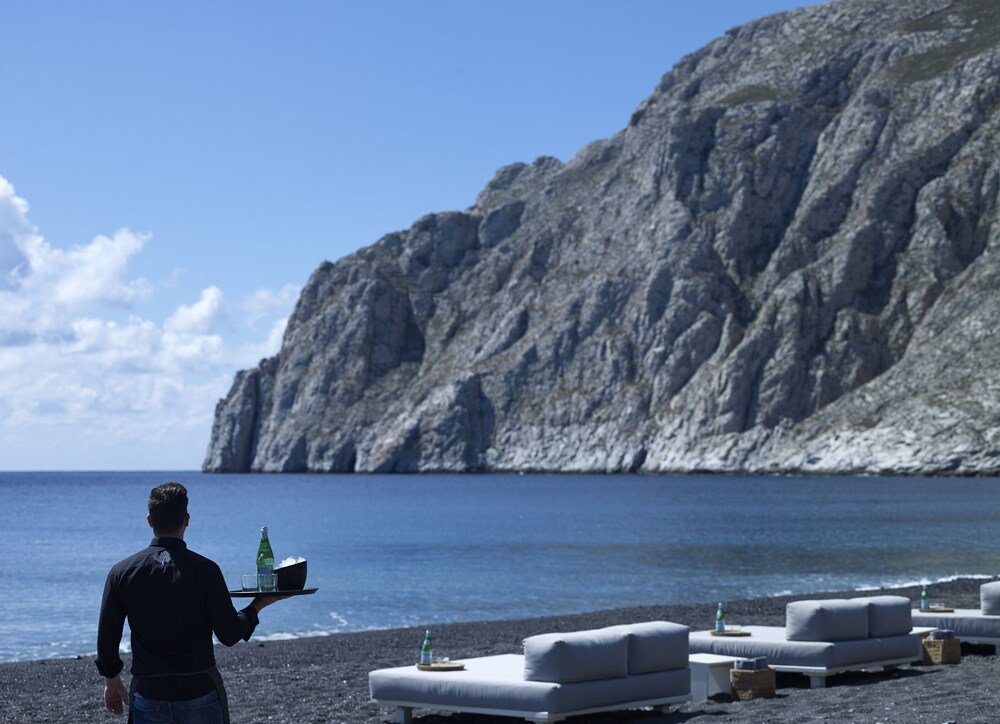 Playa con un acantilado rocoso y un empleado con una bandeja