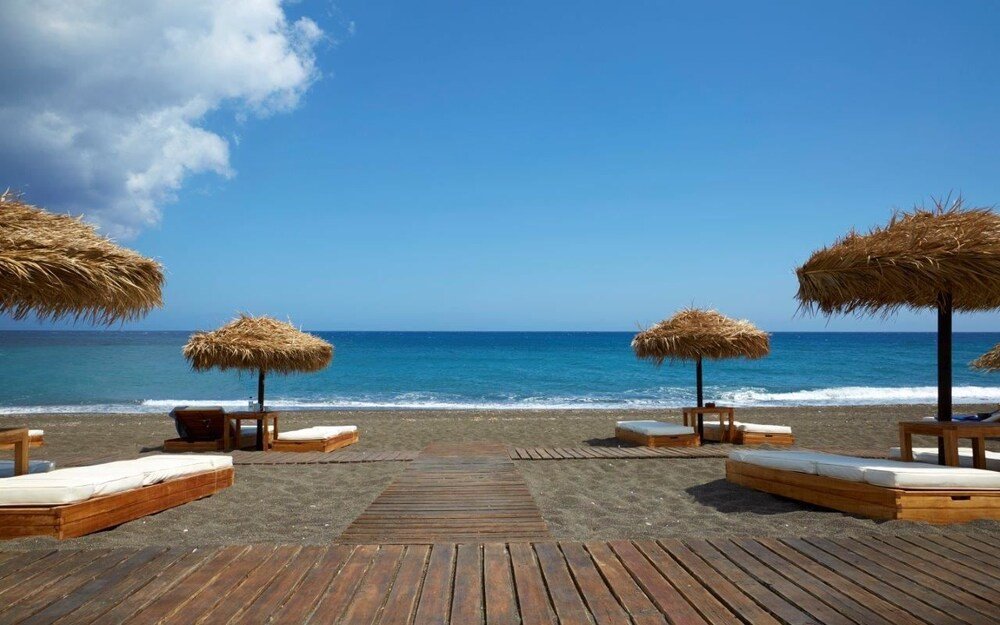 Playa con reposeras de madera y sombrillas de paja