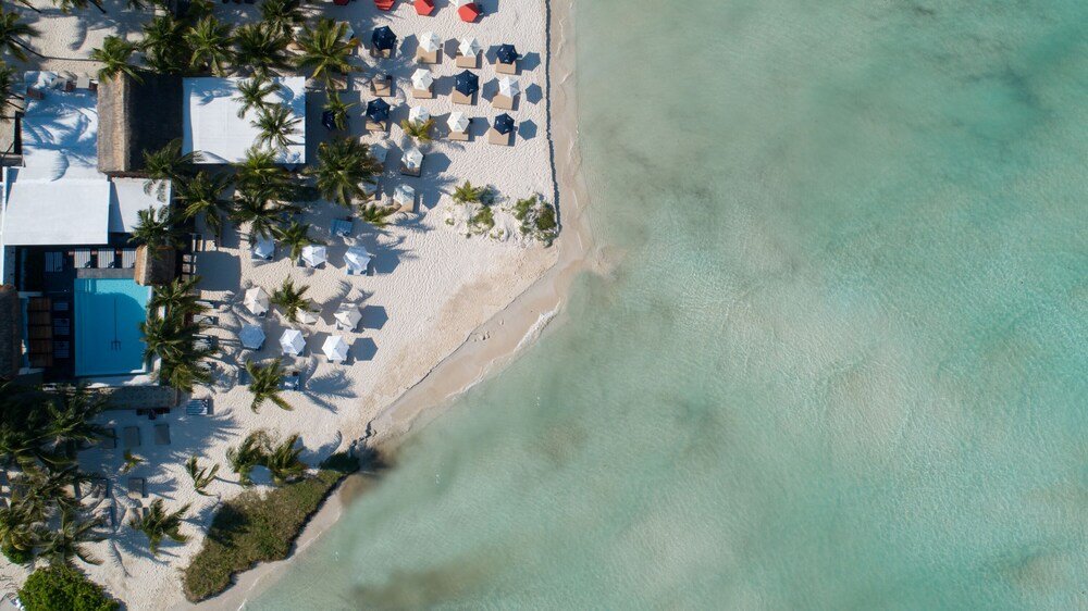 Vista aérea del hotel de playa con piscina y camastros