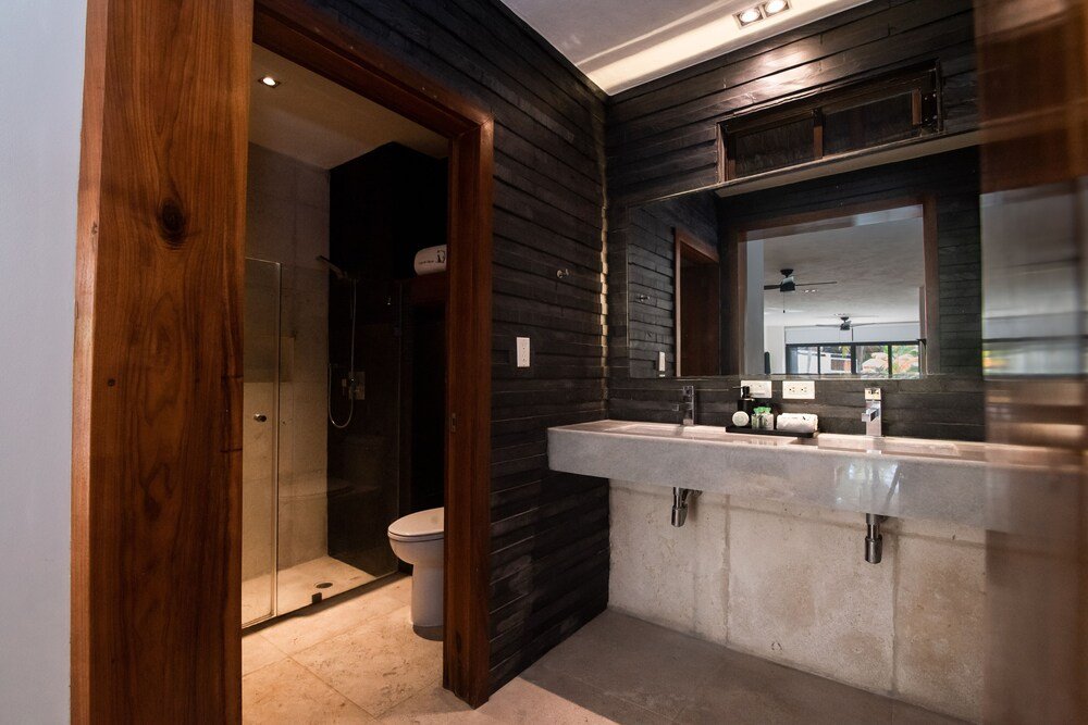 Baño moderno con tocador de madera y ducha de vidrio en Casa del Jaguar
