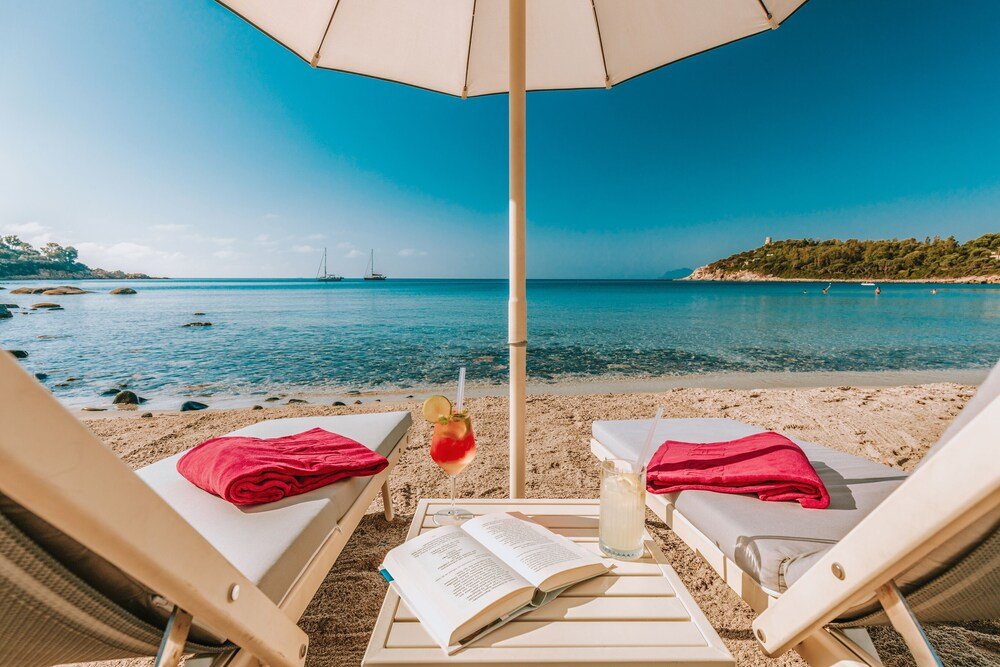 Beachside view with two sun loungers and a beach umbrella at La Bitta