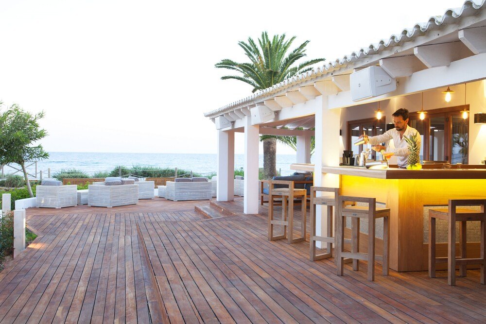 Bar exterior con deck de madera y asientos en Gecko Hotel