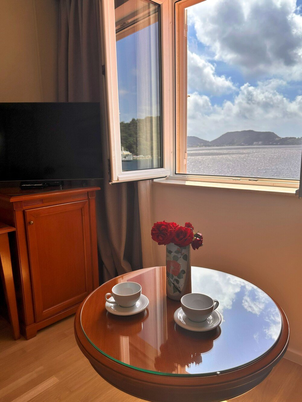 Habitación con mueble de madera, televisor y mesa de vidrio