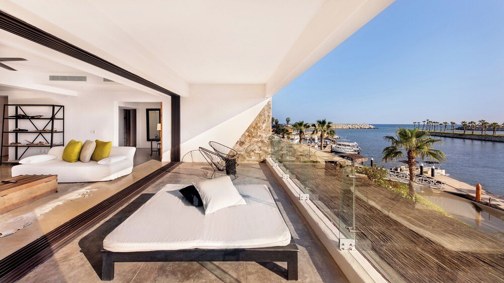 Balcón con cama, sofá blanco y mesa de centro de madera