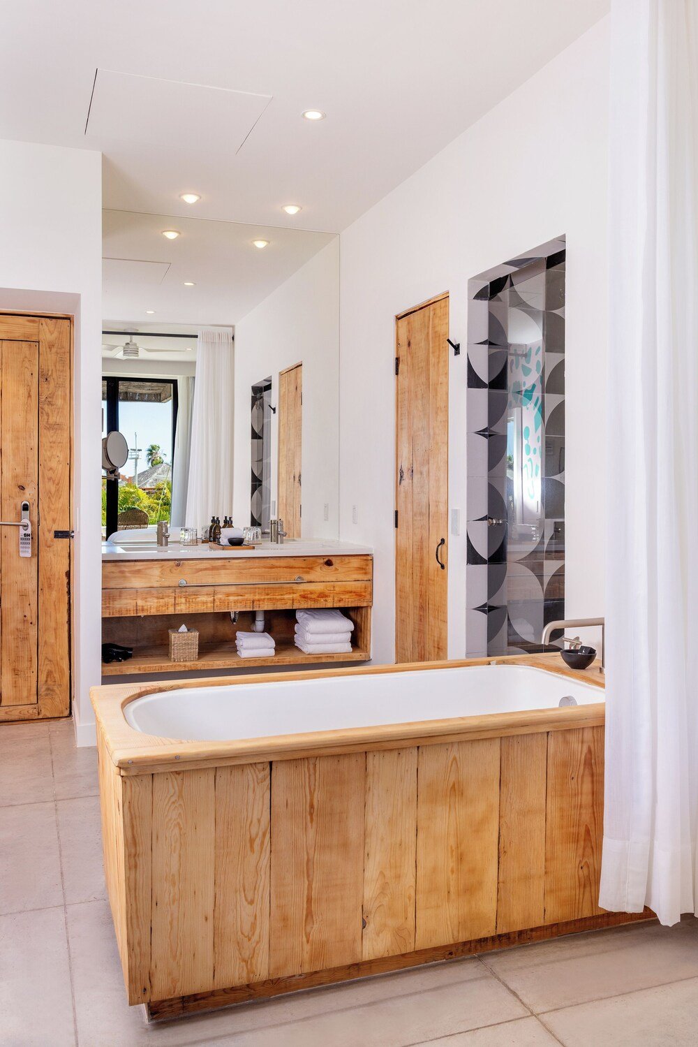 Baño moderno con bañera de madera y un gran espejo