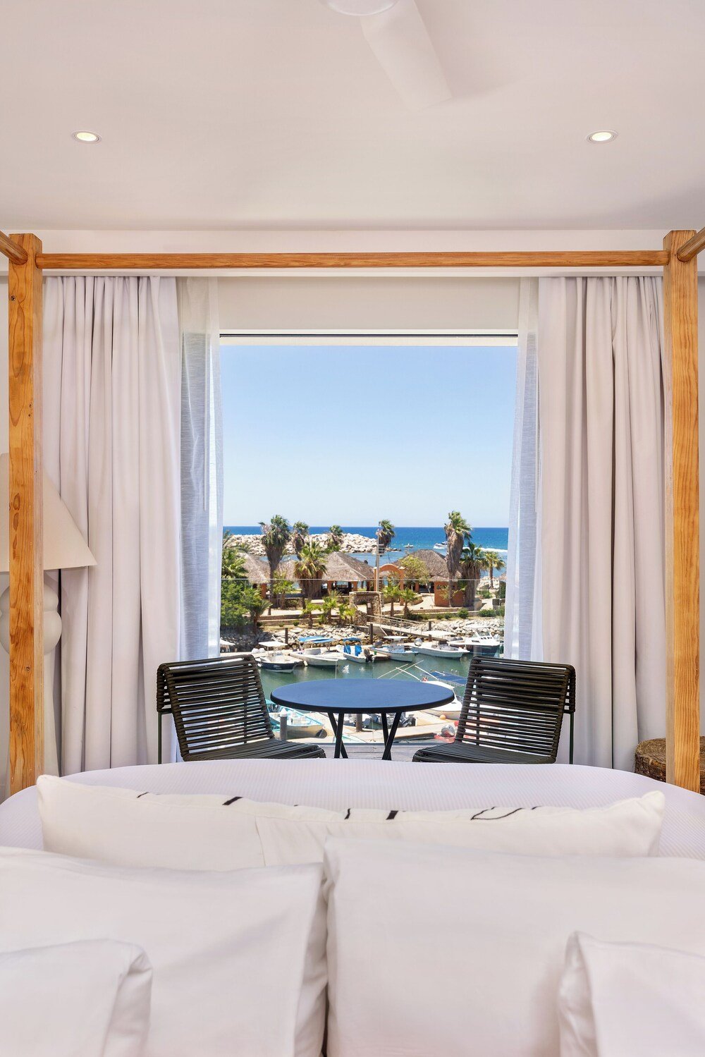 Habitación con un gran ventanal, una cama y una mesa con sillas