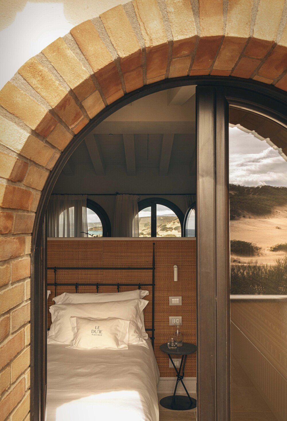 Bedroom with a brick wall and white linens