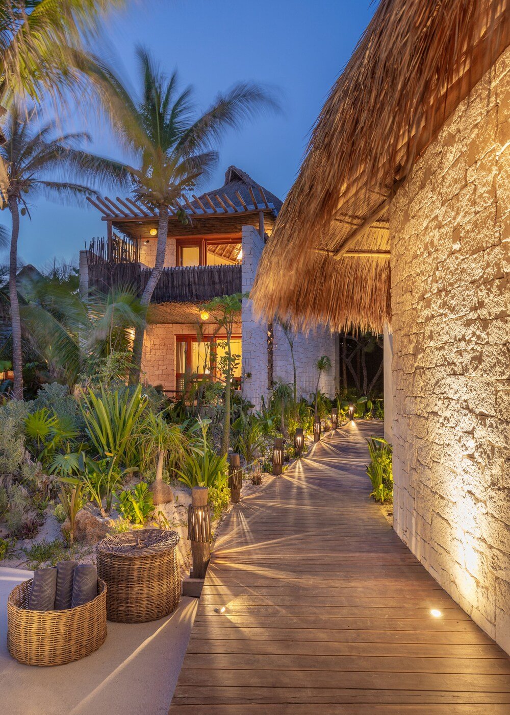 Resort with wooden deck, thatched-roof buildings and tropical landscaping