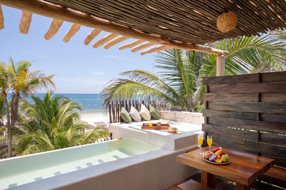 Balcón con piscina, muebles de madera y frutas y bebidas sobre una mesa