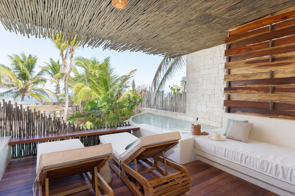 Deck de madera con piscina, reposeras y vista a palmeras y mar
