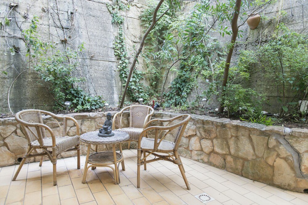 Patio exterior con muebles de mimbre y muro de piedra