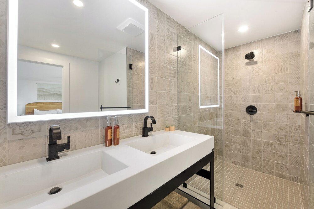 Baño moderno con un gran espejo y dos lavabos