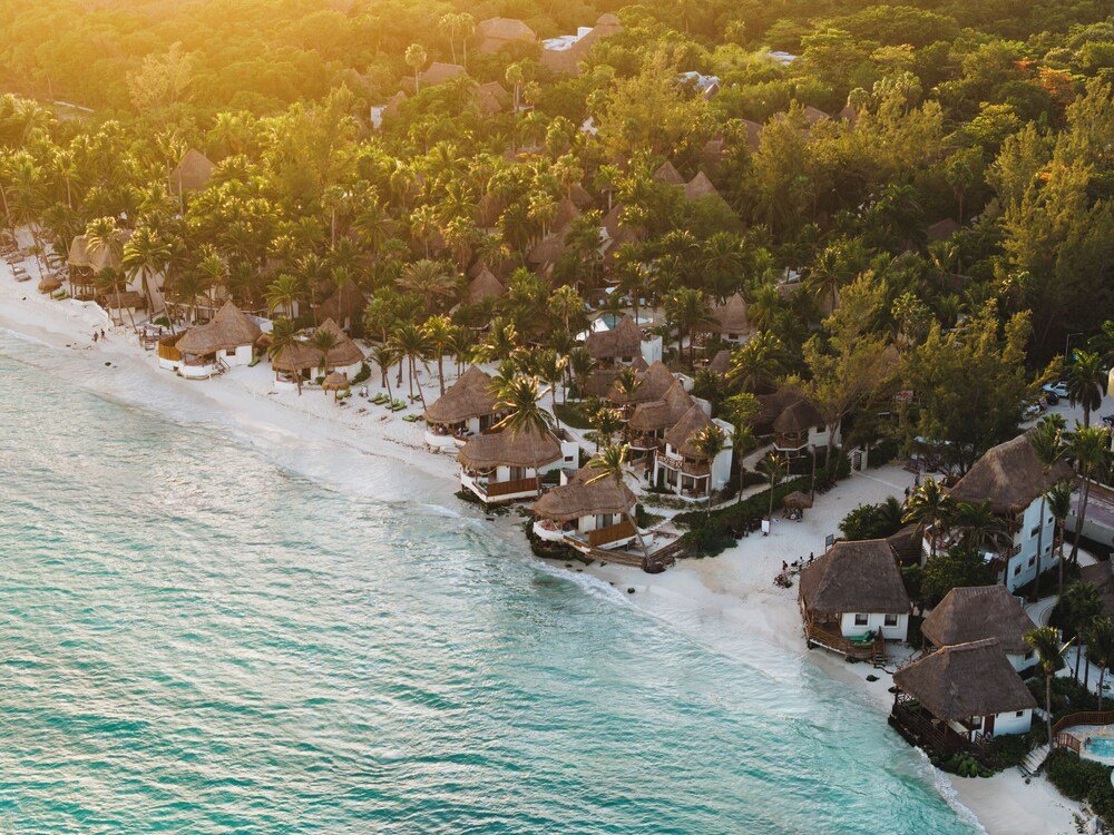 Coastal resort with thatched-roof cottages, sandy beach and lush greenery