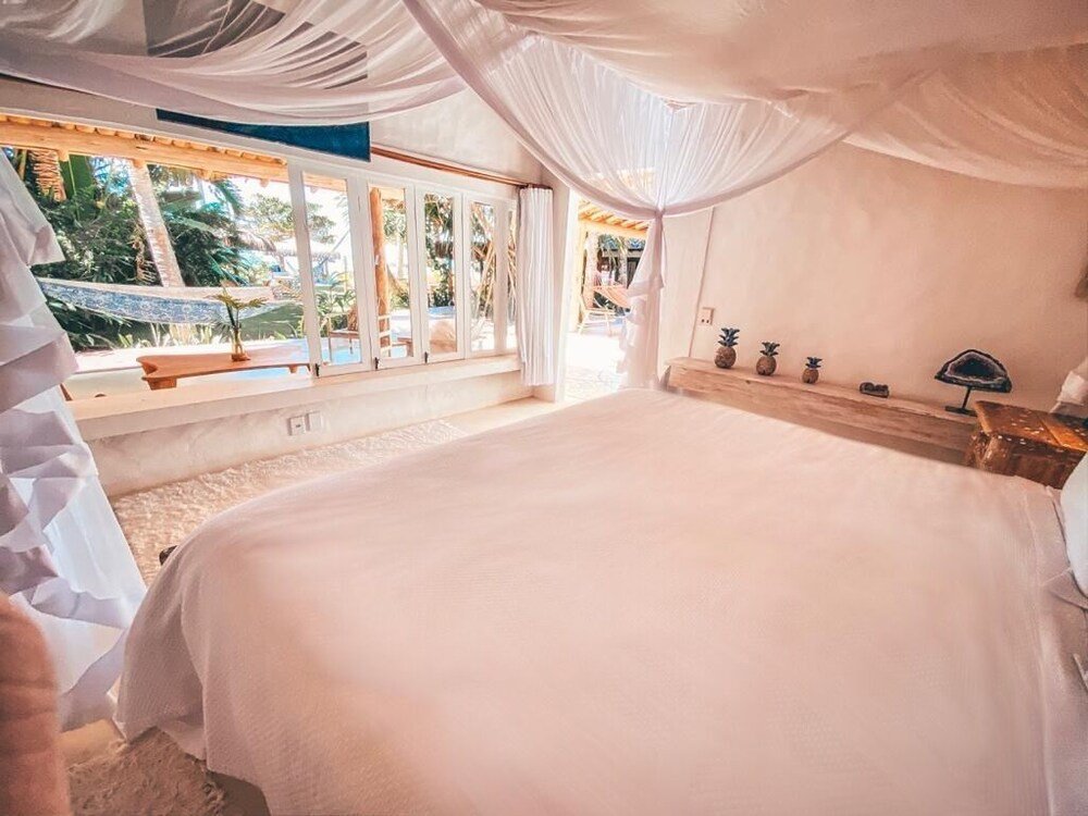 Dormitorio con una cama grande y una ventana con cortinas