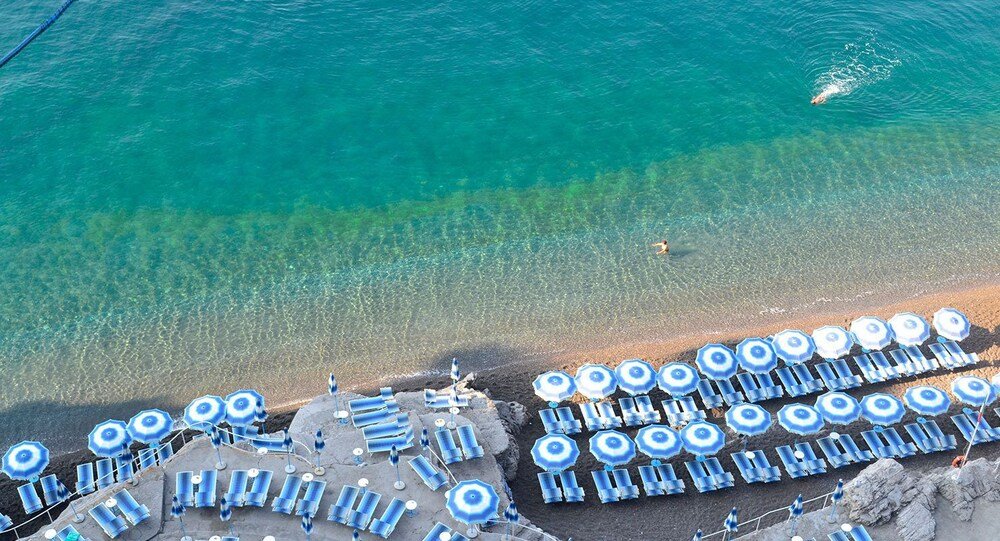 Aerial view of a beach with rows of blue umbrellas
