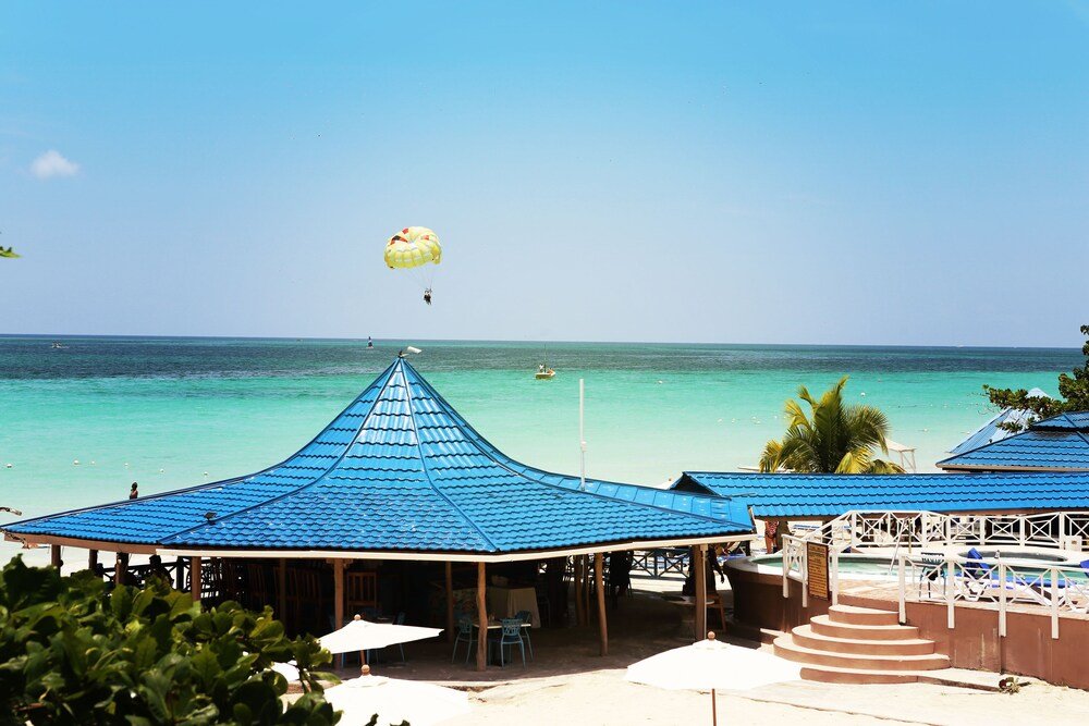 Beachside area with blue-roofed structures at Negril Tree House Resort, Jamaica