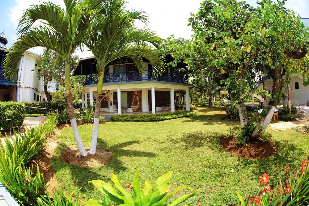 Two-storey building with a balcony surrounded by greenery