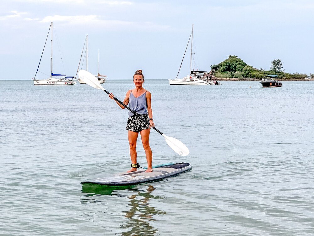 Persona de pie sobre una tabla de paddle en aguas calmas
