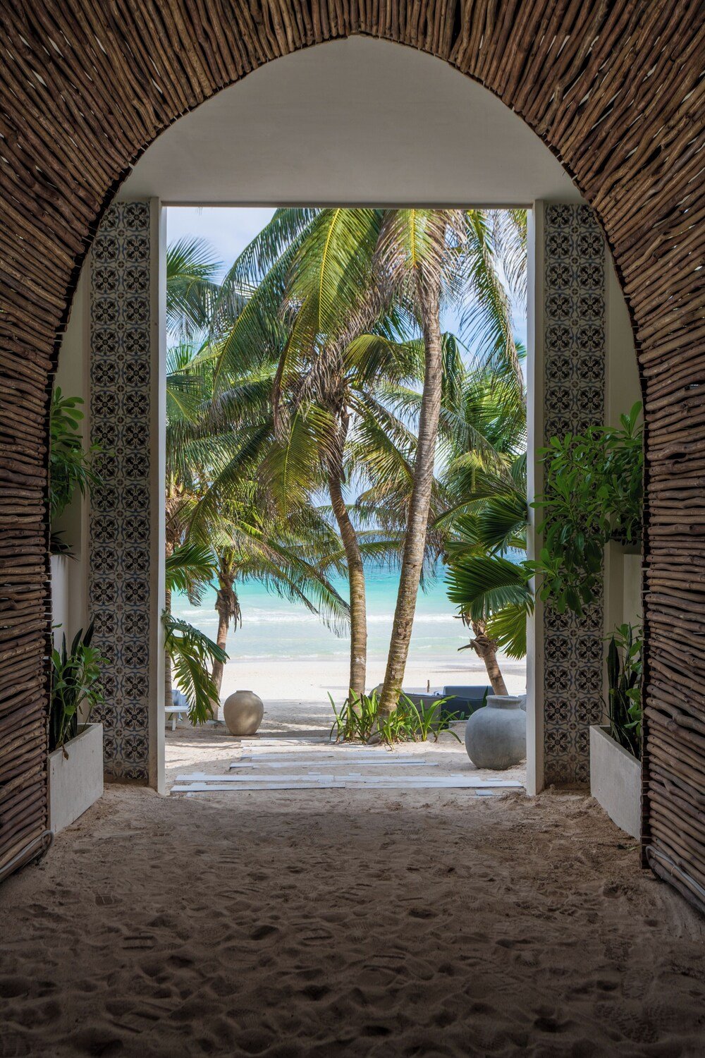 Beach view through an arched doorway with patterned walls