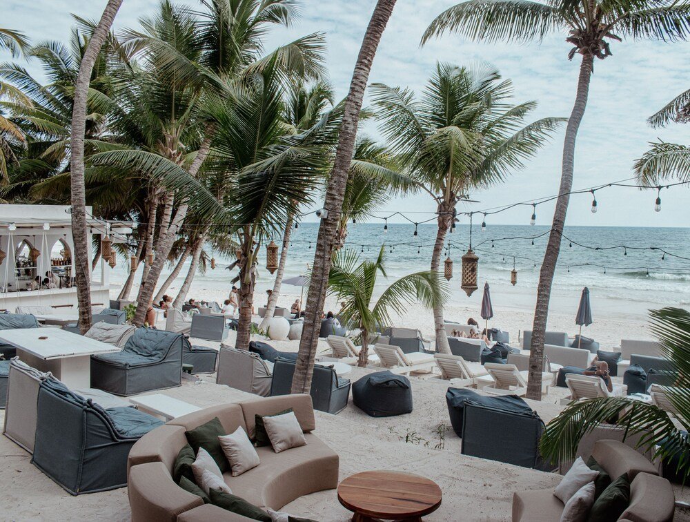 Salón junto a la playa con asientos al aire libre y palmeras