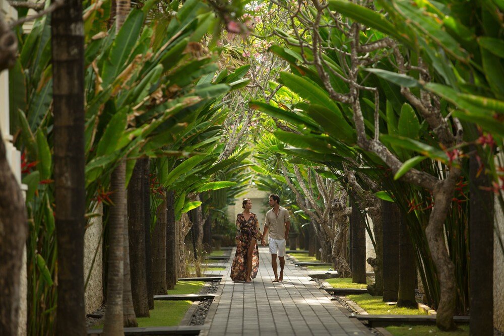 Pareja caminando por un sendero bordeado de palmeras en el resort