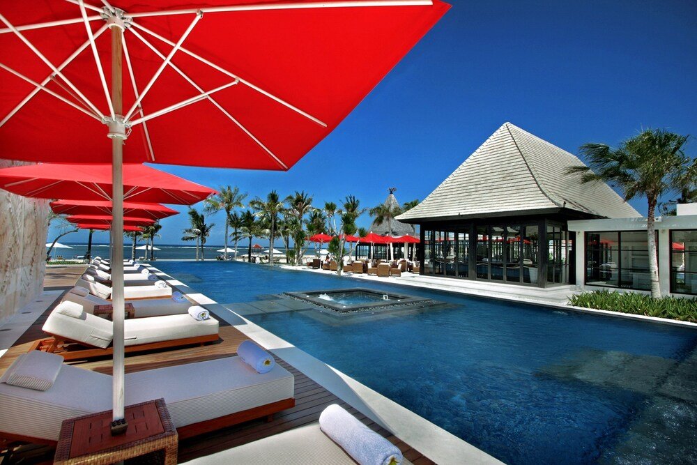 Zona junto a la piscina con tumbonas y sombrillas rojas en el resort