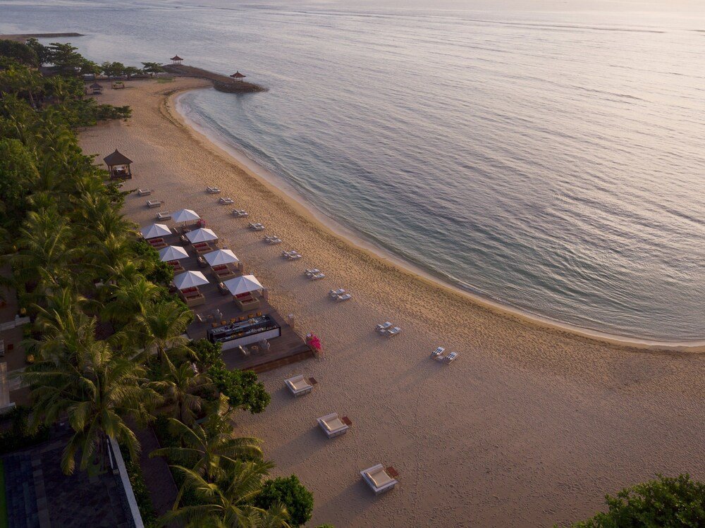Vista aérea del resort frente al mar con tumbonas sobre la arena