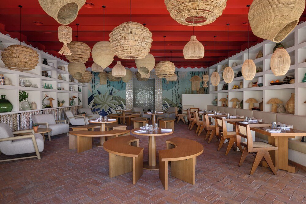 Restaurante con mesas redondas y sillas de mimbre en el hotel
